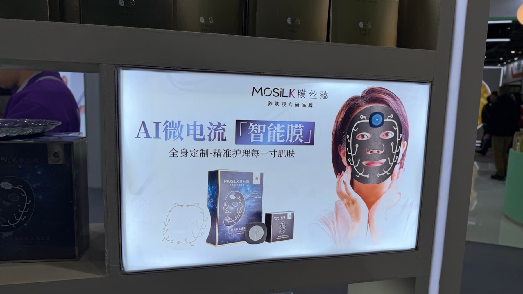 A MOSILK display advertising an AI microcurrent smart facial mask.